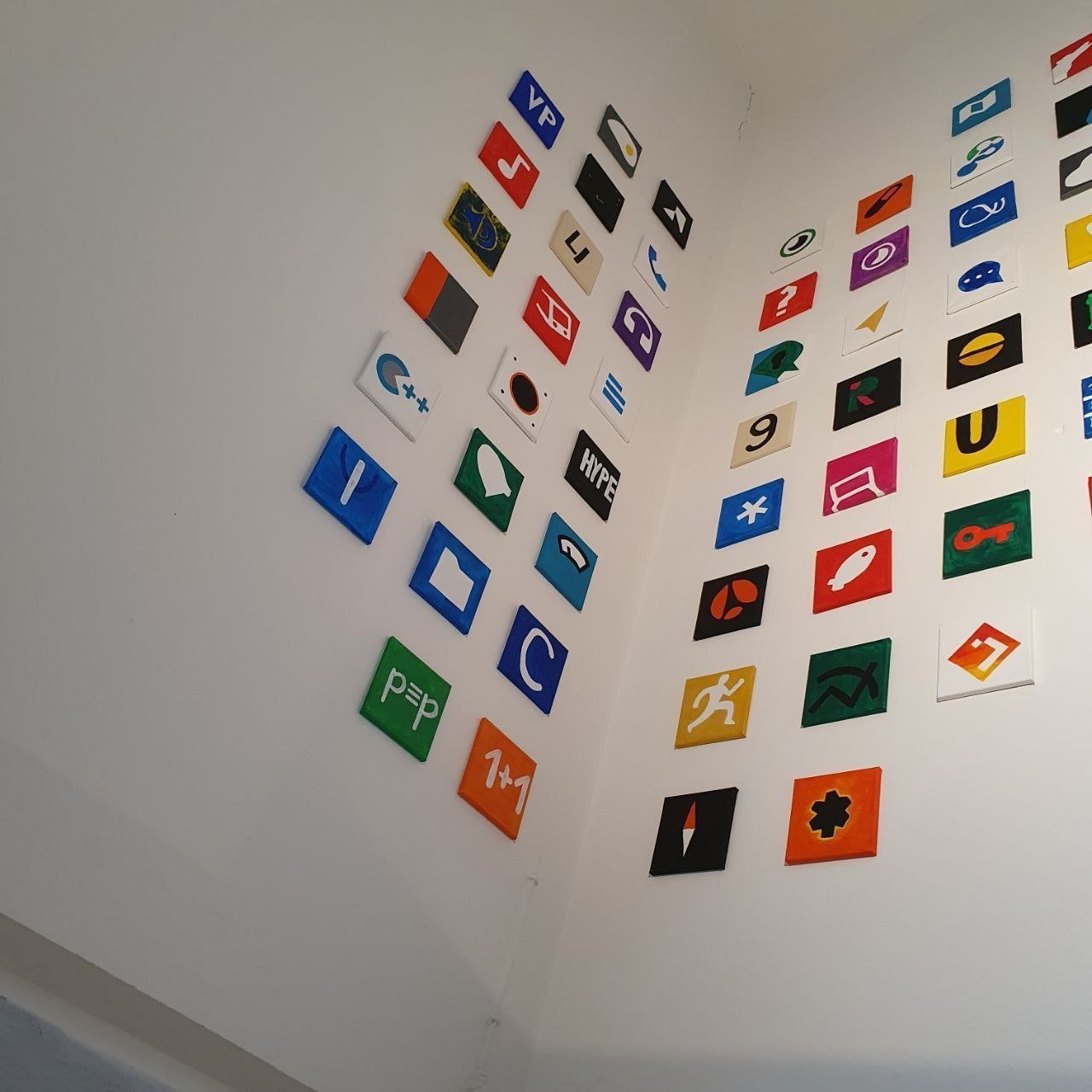 A gallery wall at mondstern's first exhibition in Berlin, covered in dozens of small brightly coloured square acrylic paintings of app icons